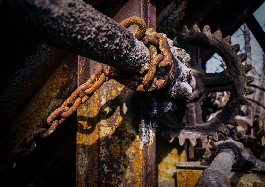 Close-up of rusty chains and gears in an abandoned industrial area.