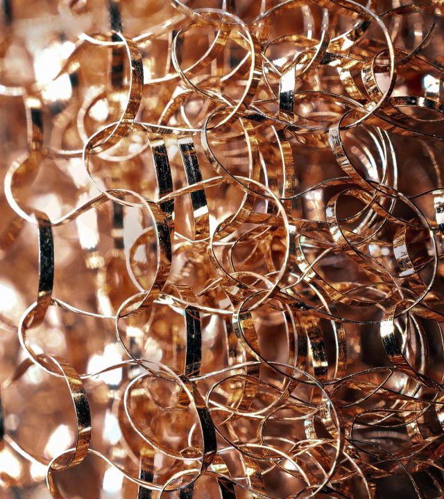 Entangled metal wire with rounded edges and glowing surface on blurred background in twilight